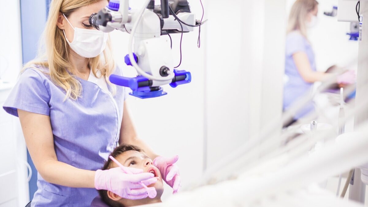 young female dentist examining boy s teeth through microscope 23 2147906006